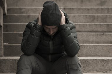 Orta yaşlı, üzgün ve depresif, işsiz bir adamın karanlık ve sinirli şehir portresi. Kirli sokak köşesindeki merdivenlerde oturmuş depresyon sorunu yaşıyor.
