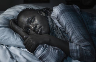 Genç hasta ve depresif zenci Amerikalı kızın dramatik ev portresi. Geceleri yatakta üzgün ve uykusuz. Bunalım ve anksiyete sorunları yaşıyor.