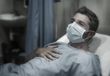 Çekici ve korkmuş bir adamın dramatik sanatsal portresi kovid 19 tarafından enfekte edilmiş - yüz maskeli yetişkin erkek Coronavirus Solunum Bozukluğu tedavisi görüyor
