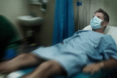 Çekici ve korkmuş bir adamın dramatik sanatsal portresi kovid 19 tarafından enfekte edilmiş - yüz maskeli yetişkin erkek Coronavirus Solunum Bozukluğu tedavisi görüyor