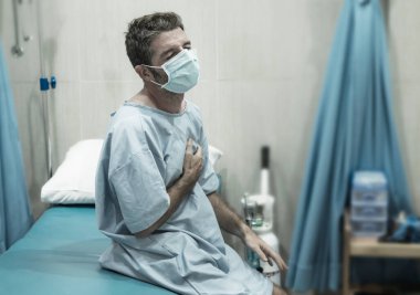 Çekici ve korkmuş bir adamın sanatsal portresi. Kovid 19 tarafından enfekte edilmiş. Klinikte yüz maskesi takmış yetişkin bir erkek.