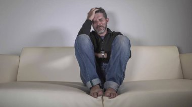 40 'lı yaşlarında depresyonda ve çaresiz bir adam kanepede ağlıyor kafası karışık ve sıkıntılı depresyon sorunu ve bunalım krizi yaşıyor.