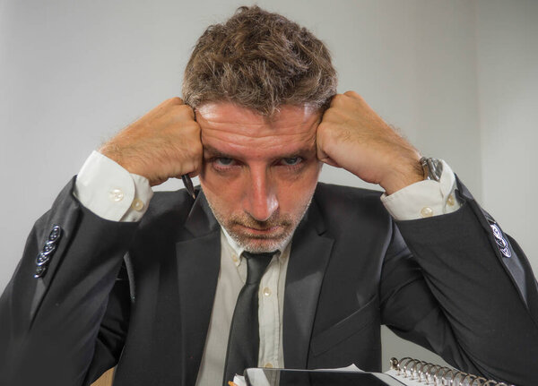 upset and depressed businessman at office desk - young unhappy man working frustrated suffering stress and depression as employee of corporate business looking unsatisfied