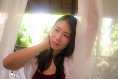 Lüks otel odasındaki balkonda rahat ve keyifli tatil ve seyahat kavramının tadını çıkaran mutlu ve güzel Asyalı bir kadının arka ışıklandırılmış hayali portresi.