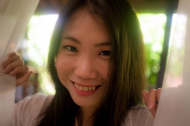 Lüks otel odasındaki balkonda rahat ve keyifli tatil ve seyahat kavramının tadını çıkaran mutlu ve güzel Asyalı bir kadının arka ışıklandırılmış hayali portresi.