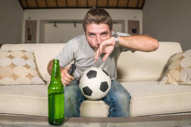 Futbolcu destekçisi televizyondaki maçtan zevk alıyor. Sinirli ve çekici bir futbol fanatiği, televizyon seyrediyor. Kanepede kanepe izliyor. Spor duyguları konseptinde bira şişesi içiyor.