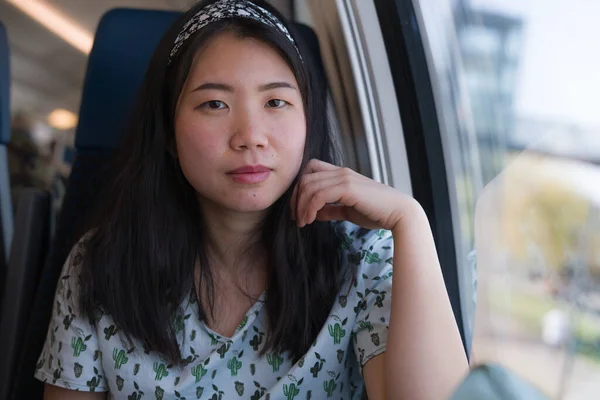 train travel getaway - lifestyle portrait of young happy and beautiful Asian Korean woman traveling on railway looking through window