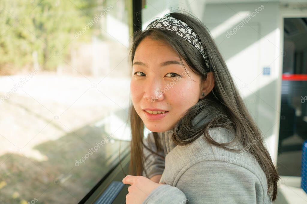 train travel getaway - lifestyle portrait of young happy and beautiful Asian Korean woman traveling on railway looking through window relaxed and cheerful