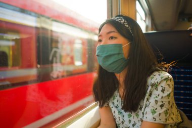 Tren yolculuğu, 19 yaşında mutlu ve tatlı Asyalı kadın maske takmış tren vagonunda seyahat ederken pencereden manzarayı seyrediyor ve tatil kaçamağının keyfini çıkarıyordu.