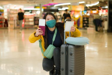19 kez uçan Asyalı bir kadın. Yüz maskeli, sarı ceketli, mutlu ve güzel bir Çinli kızın hayat tarzı portresi. Tatil için havaalanı salonunda bekliyor. 