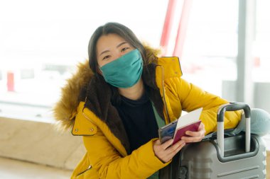 19 kez uçan Asyalı bir kadın. Yüz maskeli, sarı ceketli, mutlu ve güzel bir Çinli kızın hayat tarzı portresi. Tatil için havaalanı salonunda bekliyor. 