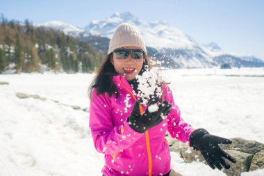 Noel tatili boyunca güzel dağlarda karla oynamaktan hoşlanan genç mutlu ve çekici Asyalı bir Çinli kadının açık hava yaşam tarzı portresi.
