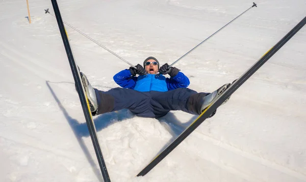 lifestyle portrait of young happy and funny man in cross country ski lying on snow playful enjoying winter holidays on Swiss Alps having fun