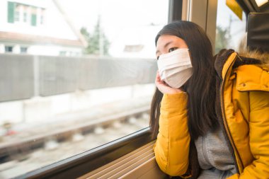 Korunmak için maske takmış güzel ve düşünceli Asyalı bir kadının hayat tarzı portresi.