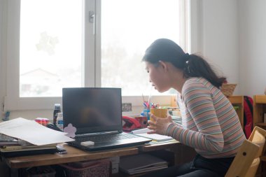 Uzaktan kumandalı iş. Genç mutlu ve güzel Asyalı bir kadının portresi. Ev bilgisayarında çalışırken kahve içerken gülümsüyor.