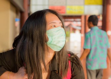 Covid-19 döneminde seyahat ve tatil. Sırt çantalı güzel Asyalı bir kadın havalimanında bekliyor. Covid19 virüsüne karşı koruyucu maske takıyor.