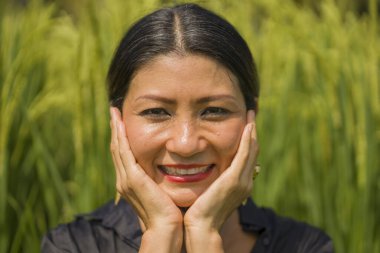 Çekici ve mutlu Asyalı kadının sanatsal portresi yeşil pirinç tarlasında zarif uzun elbiseler giyerek güzel doğanın tadını çıkarıyor. 