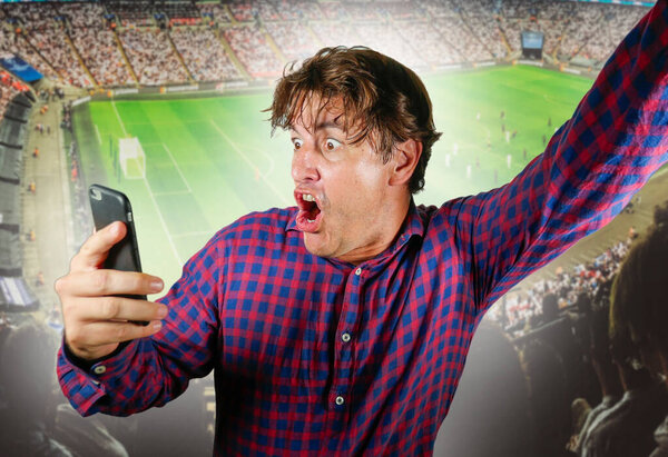 conceptual composite with happy and excited man with mobile phone and soccer background in online sport bet and internet gambling concept winning and making money
