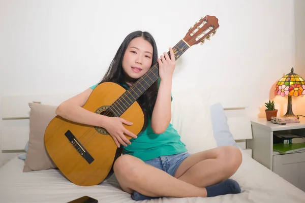Νεαρή Ευτυχισμένη Ασιατική Γυναίκα Παίζει Κιθάρα Στο Κρεβάτι Ελκυστική Και — Φωτογραφία Αρχείου
