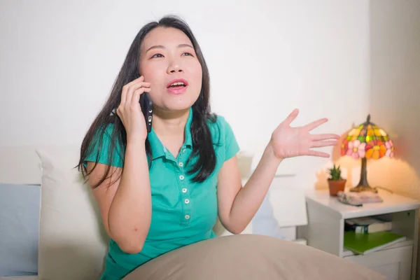 幸せな若いと魅力的なアジアの韓国人女性の家のライフスタイルのポートレートベッドの上に座っている携帯電話で話している彼女のゴシップ陽気でリラックスした — ストック写真