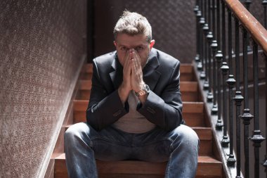 İşsizlik ve boşanma - 40 'lı yaşlarda üzgün ve depresif bir adamın dramatik bir hayat portresi. Kapalı bir merdivende oturmuş düşünceli ve endişeli depresyon sorunu yaşıyor. 