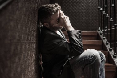 İşsizlik ve boşanma - 40 'lı yaşlarda üzgün ve depresif bir adamın dramatik bir hayat portresi. Kapalı bir merdivende oturmuş düşünceli ve endişeli depresyon sorunu yaşıyor. 