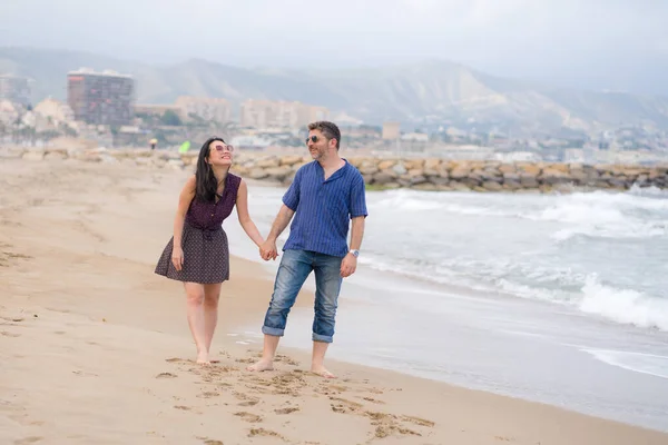 young beautiful and happy mixed ethnicity couple of Asian woman and Caucasian man relaxed and cheerful walking playful  on beach enjoying love and romantic holidays