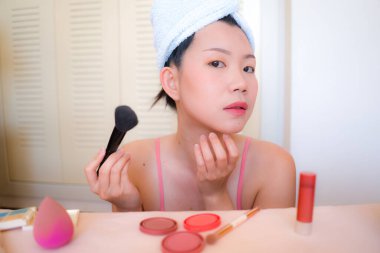 Asyalı kadın ve makyaj. Havluyla sarılıp banyodaki aynaya güzellik ve moda konseptiyle bakan genç, mutlu ve güzel Japon kız.