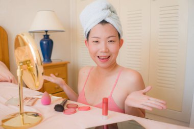 Güzel ve mutlu Asyalı bir Çinli kadın havluyla makyaj yapıyor aynaya bakıp gülümsüyor ve güzellik modasına hazırlanıyor.