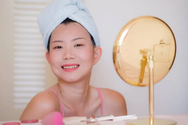 若いです美しいと幸せなアジアの中国人女性でタオルヘッドラップ化粧を適用する鏡を探して笑顔陽気に準備のためにデートのために美容ファッションの概念 — ストック写真
