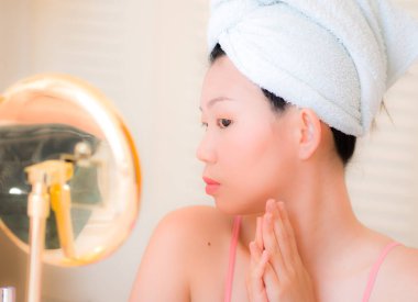 Genç Asyalı bir kadın makyaj yapıyor. Kafasında havlu olan güzel ve çekici bir Japon kız. Sabahları evde makyaj yapıyor.