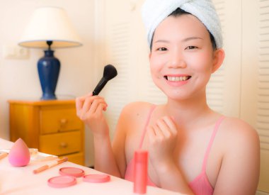 Genç Asyalı bir kadın makyaj yapıyor. Kafasında havlu olan güzel ve çekici bir Japon kız. Sabahları evde makyaj yapıyor.