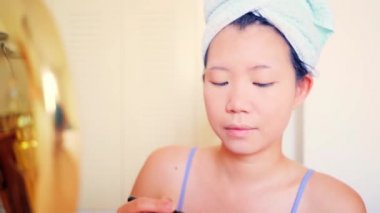 Asyalı kadın ve makyaj - güzel ve mutlu bir Koreli kızın yaşam tarzı portresi havluyla sarılıp aynanın yanındaki güzel ve moda konseptine sarmalanmış