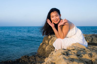 Mavi deniz kıyısında genç bir Asyalı kadın. Mutlu ve güzel bir Çinli kız. Tatil tatilinin tadını çıkarıyor.