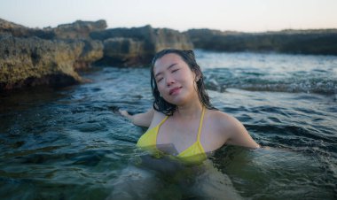 Sarı bikinili güzel Koreli kız tropikal ada tatillerinin tadını çıkarıyor.