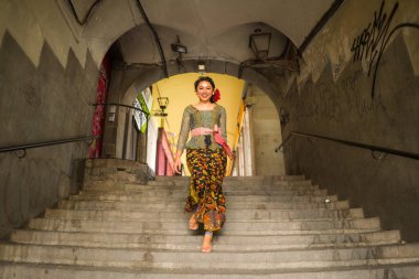 Genç ve güzel Asyalı kadın geleneksel Balili kebaya elbisesi giyiyor - Bali elbiseli Endonezyalı kız Avrupa 'da tatil gezileri sırasında sokakta yürüyor
