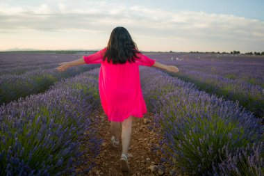 Genç mutlu ve güzel bir kadının arka portresi. Yaz elbisesi içinde. Doğanın tadını çıkarıyor.