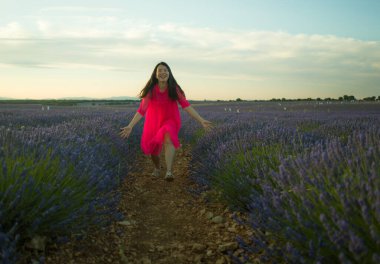 Genç ve güzel Asyalı yaz elbiseli kadın romantik güzellik ve özgürlük konseptiyle mor lavanta çiçeklerinin olduğu yerde doğanın tadını çıkarıyor.
