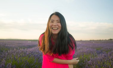 Genç ve güzel Asyalı yaz elbiseli kadın romantik güzellik ve özgürlük konseptiyle mor lavanta çiçeklerinin olduğu yerde doğanın tadını çıkarıyor.