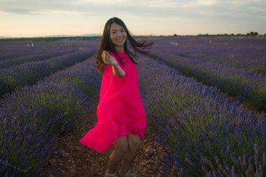 Genç ve güzel Asyalı yaz elbiseli kadın romantik güzellik ve özgürlük konseptiyle mor lavanta çiçeklerinin olduğu yerde doğanın tadını çıkarıyor.