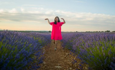 Genç ve güzel Asyalı yaz elbiseli kadın romantik güzellik ve özgürlük konseptiyle mor lavanta çiçeklerinin olduğu yerde doğanın tadını çıkarıyor.