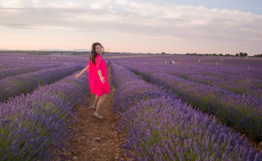 Genç ve güzel Asyalı yaz elbiseli kadın romantik güzellik ve özgürlük konseptiyle mor lavanta çiçeklerinin olduğu yerde doğanın tadını çıkarıyor.