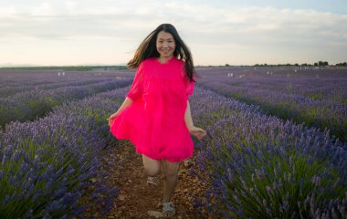 Genç ve güzel Asyalı yaz elbiseli kadın romantik güzellik ve özgürlük konseptiyle mor lavanta çiçeklerinin olduğu yerde doğanın tadını çıkarıyor.