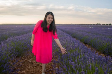 Genç ve güzel Asyalı yaz elbiseli kadın romantik güzellik ve özgürlük konseptiyle mor lavanta çiçeklerinin olduğu yerde doğanın tadını çıkarıyor.