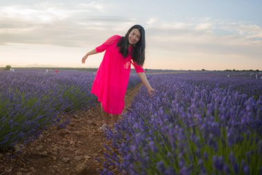 Genç ve güzel Asyalı yaz elbiseli kadın romantik güzellik ve özgürlük konseptiyle mor lavanta çiçeklerinin olduğu yerde doğanın tadını çıkarıyor.