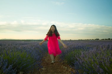 Genç ve güzel Asyalı yaz elbiseli kadın doğanın tadını çıkarıyor. Açık havada, mor lavanta çiçeklerinin olduğu yerde romantik güzellik ve özgürlük kavramında.