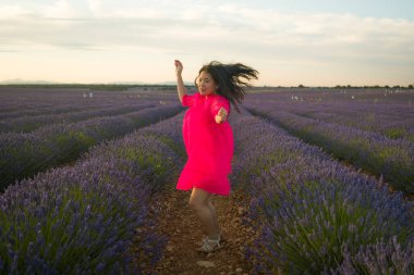 Genç ve güzel Asyalı yaz elbiseli kadın doğanın tadını çıkarıyor. Açık havada, mor lavanta çiçeklerinin olduğu yerde romantik güzellik ve özgürlük kavramında.