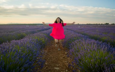 Genç ve güzel Asyalı yaz elbiseli kadın doğanın tadını çıkarıyor. Açık havada, mor lavanta çiçeklerinin olduğu yerde romantik güzellik ve özgürlük kavramında.