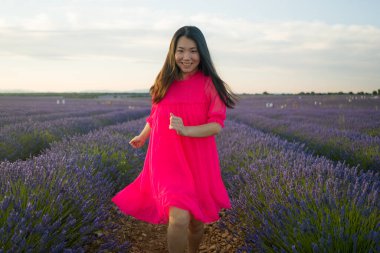 Genç ve güzel Asyalı yaz elbiseli kadın doğanın tadını çıkarıyor. Açık havada, mor lavanta çiçeklerinin olduğu yerde romantik güzellik ve özgürlük kavramında.