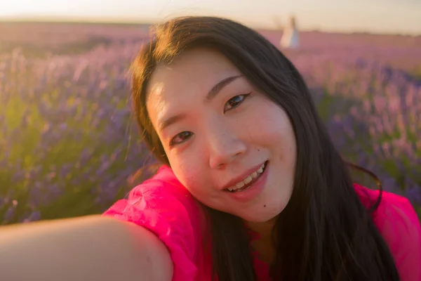 若いです幸せと美しいアジアの中国人女性で夏のドレス取る夕日セルフィーとともに携帯電話で紫ラベンダーの花のフィールドで自然とロマンチックな美しさの概念 — ストック写真